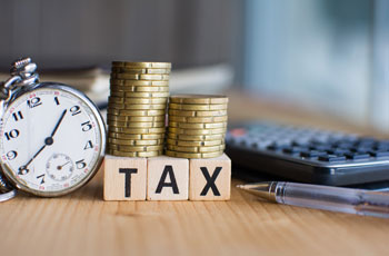 Verschiedene Gegenstaende die fuer das Master of Taxiation Studium stehen, darunter eine Stoppuhr, Geldmuenzen, ein Taschenrechner