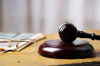 Richterhammer liegt auf dem Tisch, daneben eine Brille und Dokumente
