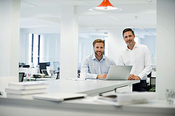 Am Empfang einer Kanzlei stehen zwei junge Steuerberater bereit