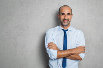 Angehender Steuerberater hat Arme ueberkreuzt und laechelt in die Kamera