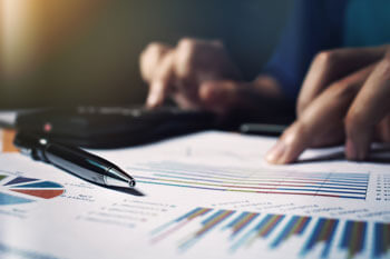 Junger Mann wertet Grafiken aus und tippt dabei in den Taschenrechner