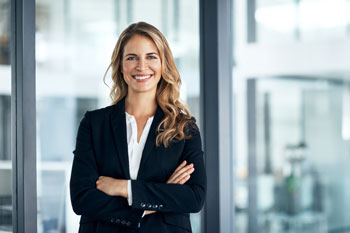 Steuerfachwirtin im Business Look hat ihre Arme gekreuzt und laechelt in die Kamera